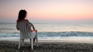 Hun sitter ved havet og mediterer med Transcendental Meditasjon